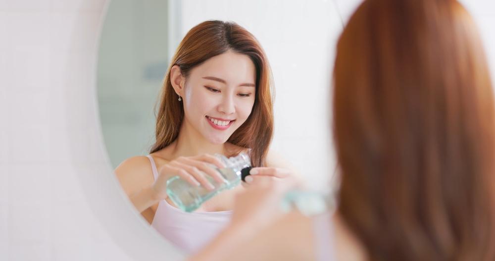 shutterstock_2264776221 หญิงสาวบ้วนปากและกลั้วคอหลังมีอาการเจ็บคอเวลากลืนน้ำลาย